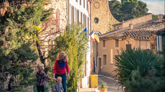 A family strolls through the village of Puyméras with the Intrigue dans la ville game.